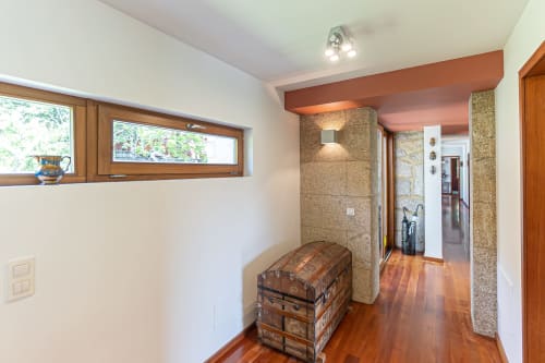 Corredor moderno da villa Quinta Trindade com piso em madeira, e vista para a montanha pela janela transom