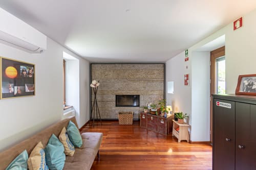 Sala de estar moderna da Quinta Trindade em Arouca com lareira, assoalho de madeira e vistas para as montanhas