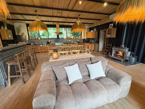 Séjour ouvert au gîte Chez Babeth du Village Du Moulin, Sizun, avec canapé beige, cuisine bois, cheminée et