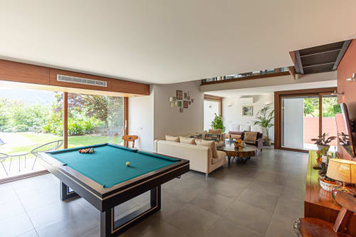 Sala de estar de villa moderna com mesa de bilhar azul, sofá creme e vista para o jardim na Quinta Trindade, Arouca