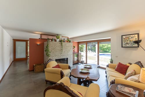 Sala espaçosa da quinta Trindade em Arouca com lareira, sofás creme e vista para a piscina do terraço