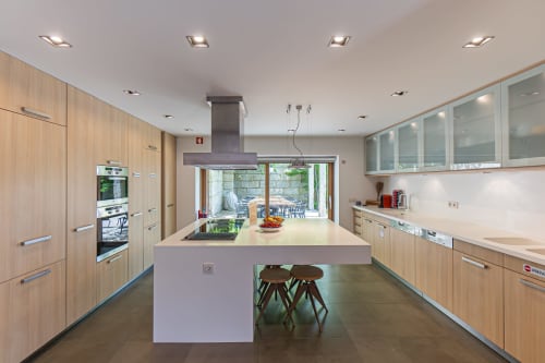 Cozinha moderna com ilha, móveis em madeira e vista para o terraço ajardinado da villa Quinta Trindade em Arouca