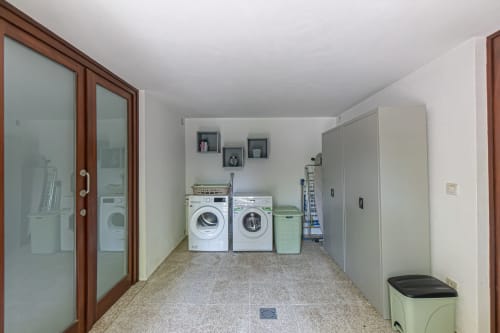 Moderna lavandaria na vila Quinta Trindade, Arouca, com máquinas de lavar, secadora e armários de armazenamento