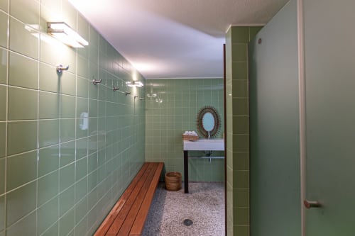 Banheiro moderno com azulejos verdes, banqueta de madeira e pia na villa Quinta Trindade em Arouca