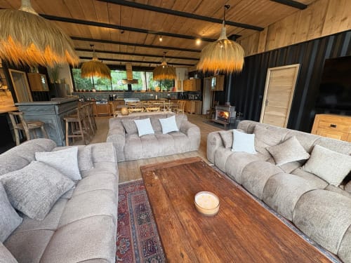 Séjour spacieux avec canapé gris, table basse en bois et cuisine ouverte du gîte Chez Babeth