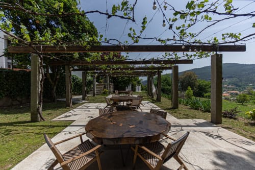 Área de refeições ao ar livre com pérgola na quinta Trindade em Arouca, com mesas de madeira, vistas de montanha e vegetação exuberante