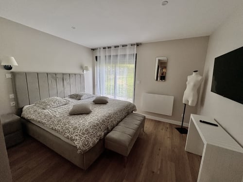 Chambre moderne à la chaumière Le Village Du Moulin à Sizun : lit queen-size, TV, vue sur jardin et mobilier contemporain