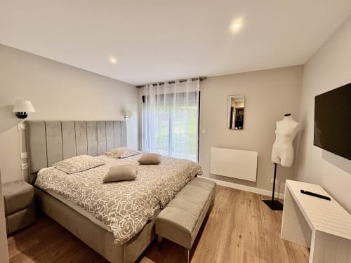 Chambre moderne à la Gîte Le Village Du Moulin à Sizun, France, avec lit queen-size, télévision écran plat et vue sur le jardin