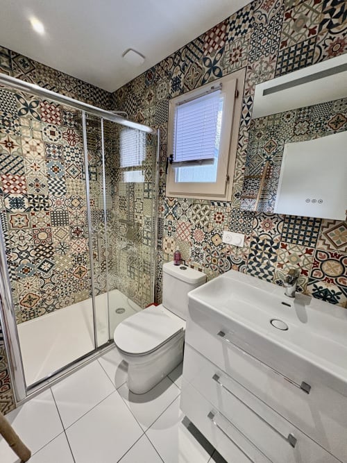 Salle de bain moderne du gîte Kerroc'h avec carrelage à motifs, vasque blanche, toilettes et douche à l'italienne.