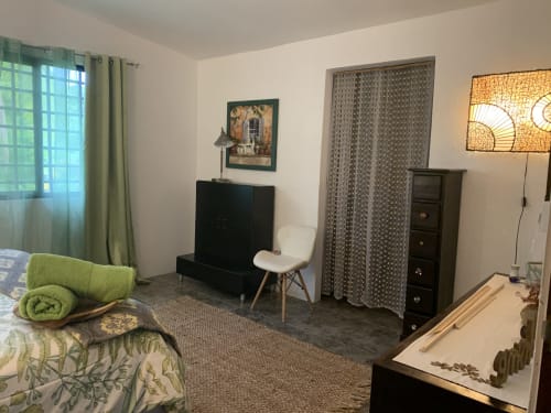 Cozy bedroom at El Litoral Panama with green accents, garden view, TV, modern chair, and patterned curtains