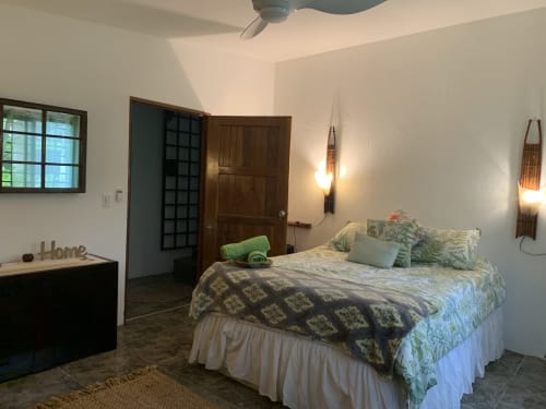 Cozy bedroom at El Litoral Panama with queen bed, green bedding, wooden doors, ceiling fan, and garden views