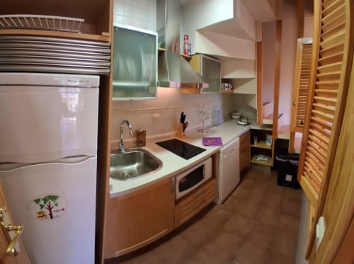 Cocina de la cabaña invernal Casa Buenavista, Sierra Nevada Granada, equipada con armarios de madera, refrigerador, estufa, fregadero y alacena