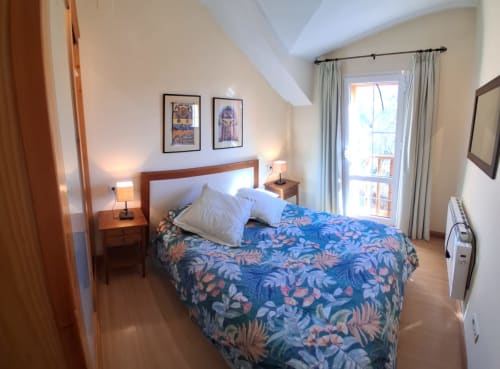 Dormitorio luminoso en la cabaña invernal Casa Buenavista en Sierra Nevada con ropa de cama floral azul, vistas montañosas y acabados de madera