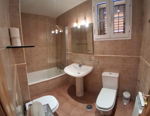 Baño moderno en cabaña invernal Casa Buenavista, Sierra Nevada Granada, con azulejos beige, bañera, lavabo pedestal, inodoro