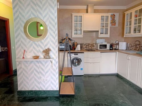 Cocina moderna del apartamento Top Home Évora en Jerez de la Frontera, con muebles blancos, lavadora y azulejos geométricos