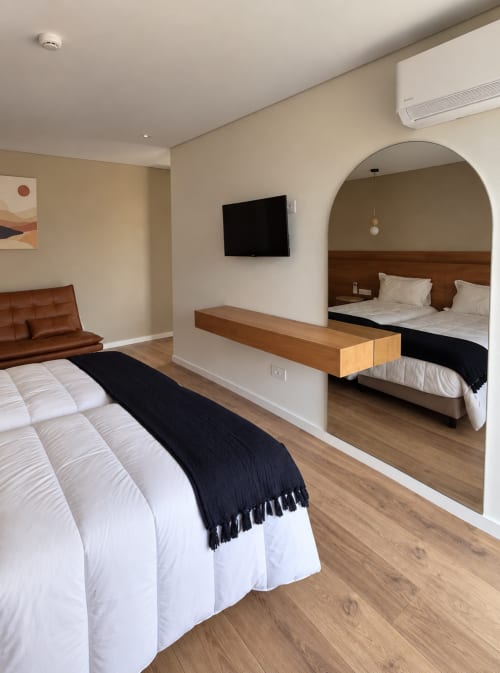 Quarto moderno da família em House Park Esposende com cama de casal, espelho, TV e detalhes em madeira marrom