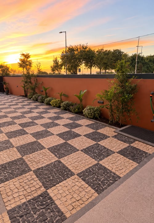 Terraço ao pôr do sol na House Park Esposende com piso em xadrez, parede laranja e vistas de montanha