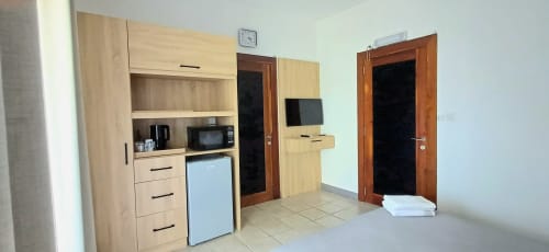Studio apartment kitchenette at Joubarbe Résidence in Moka with wooden cabinetry, microwave, refrigerator and wooden doors