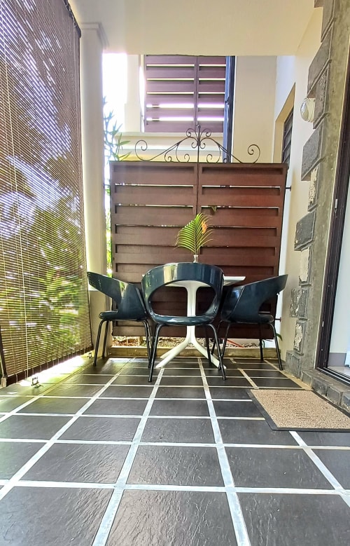Studio apartment patio at Joubarbe Résidence, Moka with black chairs, potted plant, wooden gate and tiled floor