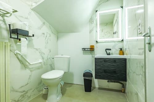 Salle de bains accessible à La villa Cassinne à Montebourg avec carrelage en marbre, équipements modernes et miroirs éclairés