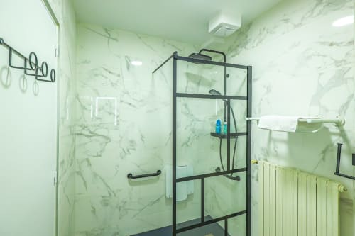 Salle de bains accessible à La villa Cassinne à Montebourg avec douche en marbre, paroi vitrée noire et porte-serviettes