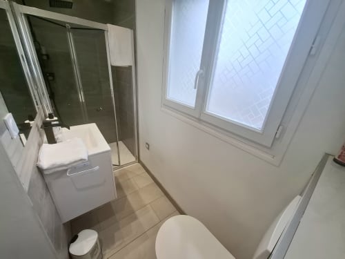 Salle de bain moderne à La villa Cassinne, Montebourg, avec lavabo blanc, toilettes et douche spacieuse à l'italienne avec paroi en verre