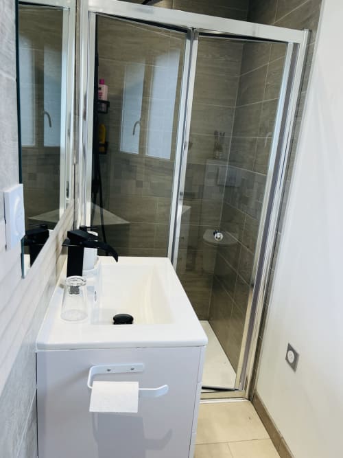Salle de bain moderne avec vanité blanche, douche à l'italienne carrelée de beige, La villa Cassinne BnB, Montebourg