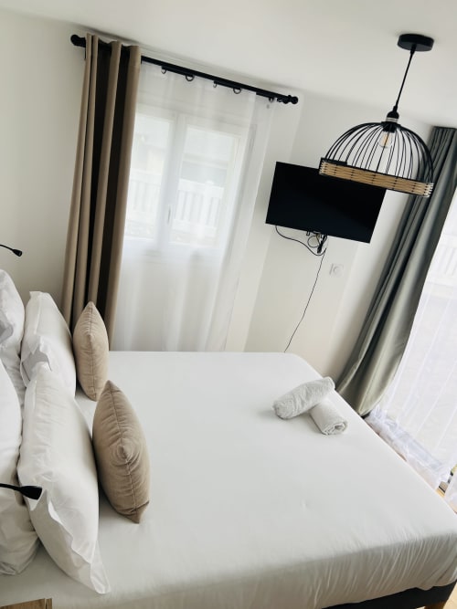 Chambre moderne à La villa Cassinne : lit king-size, draps blancs, vue sur le jardin et TV murale à Montebourg