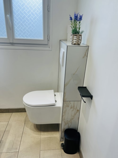 Salle de bains moderne de La villa Cassinne B&B à Montebourg avec toilettes blanches, vasque en marbre, fleurs bleues et fenêtre