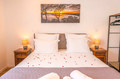 Chambre romantique king-size à La villa Cassinne, Montebourg, avec pétales de roses, tableau au coucher de soleil et accès accessible.