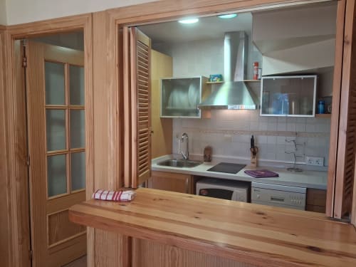 Cocina moderna en la cabaña invernal Casa Buenavista, Sierra Nevada Granada, con muebles de madera, electrodomésticos de acero inoxidable y
