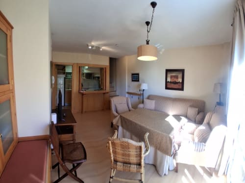 Sala de invierno Casa Buenavista con sofá rayado, cocina de madera y vistas a Sierra Nevada, Granada
