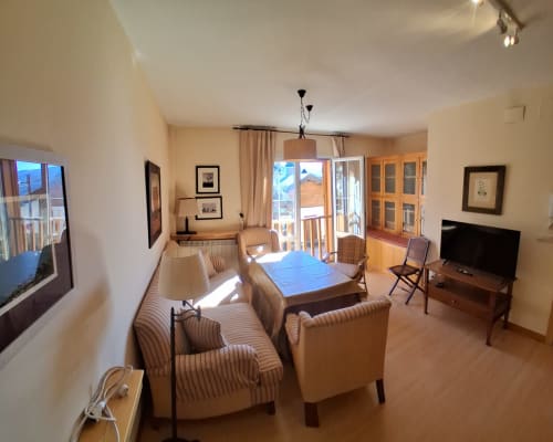 Sala de estar de la cabaña Casa Buenavista en invierno con vistas a la montaña, asientos cómodos, comedor y televisor de pantalla plana
