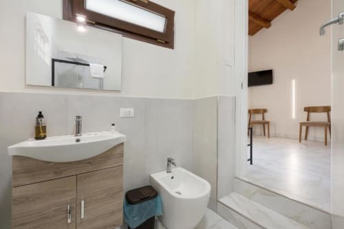 Modern bathroom in Sikania Agri Relais hotel with sink, bidet, shower, and wooden vanity