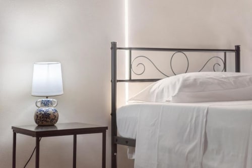 Bright bedroom at Sikania Agri Relais with metal bed frame, white linens, and decorative blue lamp on bedside table