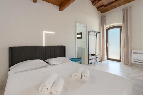 Spacious MARII Triple Room at Sikania Agri Relais in Caccamo with black headboard, white bedding, rolled towels, and mountain