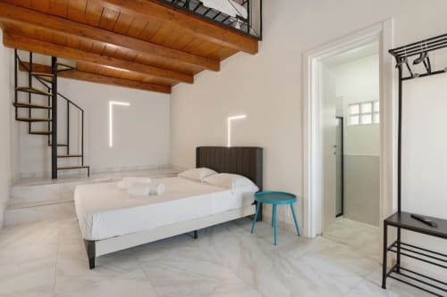 Modern bedroom at Sikania Agri Relais in Caccamo with bed, wooden beams, neon wall art, and ensuite shower