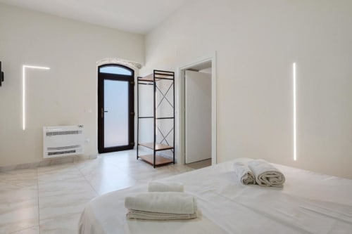 Modern bedroom at Sikania Agri Relais in Caccamo with bed, towels, metal shelving, neon lighting, and mountain view door