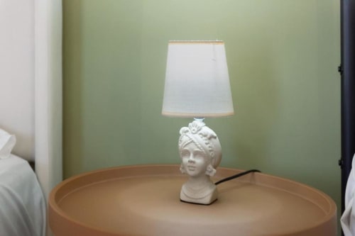White classical bust lamp with cream shade on round wood table in Sikania Agri Relais mountain view apartment