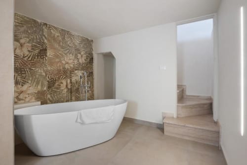 Modern bathroom in Sikania Agri Relais apartment with freestanding white bathtub and botanical tile accent wall