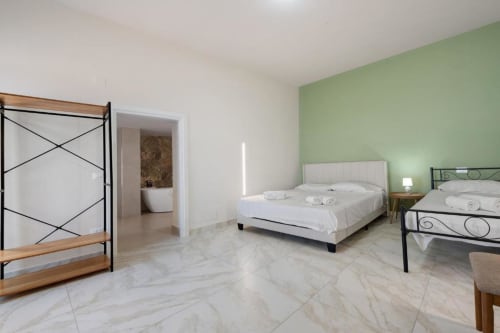 Sicilian two-bedroom apartment at Sikania Agri Relais with marble floors, green accent wall, and modern furnishings in