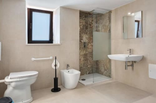 Modern bathroom in Sikania Agri Relais apartment featuring toilet, bidet, shower enclosure, and dual sinks with mirror