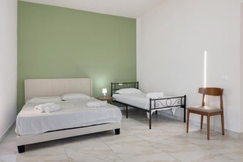 Two beds in a bright bedroom with sage green accent wall at Sikania Agri Relais, Caccamo