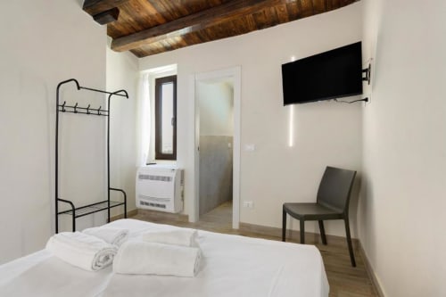 SCHIETTA Double Room at Sikania Agri Relais in Caccamo with white bed, wooden beams, wall-mounted TV, and mountain view