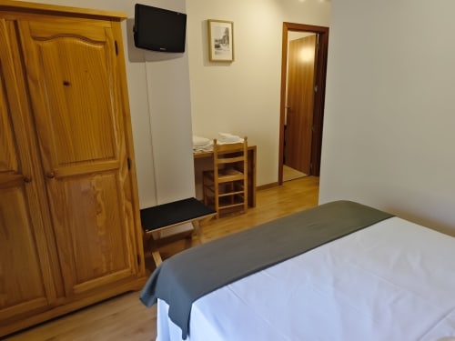 Cozy double bedroom at Balcó del Priorat hotel in Tarragona with wooden furnishings, TV, and modern amenities
