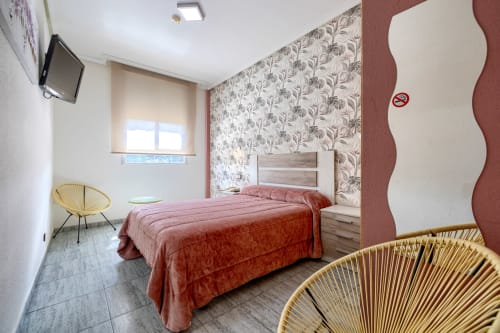 Moderna habitación doble en Hostal El Molino en Collado Villalba con ropa de cama roja, papel tapiz floral y diseño contemporáneo
