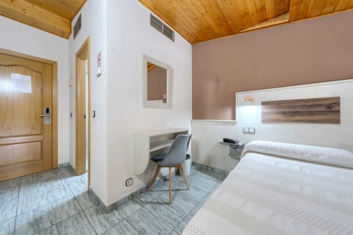 Moderno dormitorio doble en buhardilla de Hostal El Molino en Collado Villalba con techo de madera, camas gemelas y escritorio