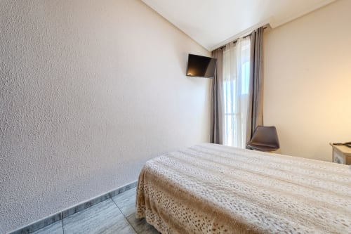 Habitación moderna en Hostal El Molino de Collado Villalba con cama, TV mural, balcón con vistas a la sierra y escritorio