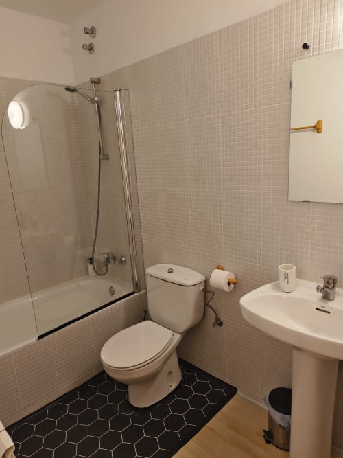 Modern bathroom at Balcó del Priorat hotel in Tarragona with shower, toilet, sink and black hexagonal floor tiles