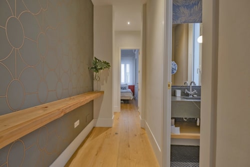 Pasillo de apartamento moderno en Madrid con papel tapiz geométrico, estantería de madera y vista al dormitorio en Andimi Apartamentos